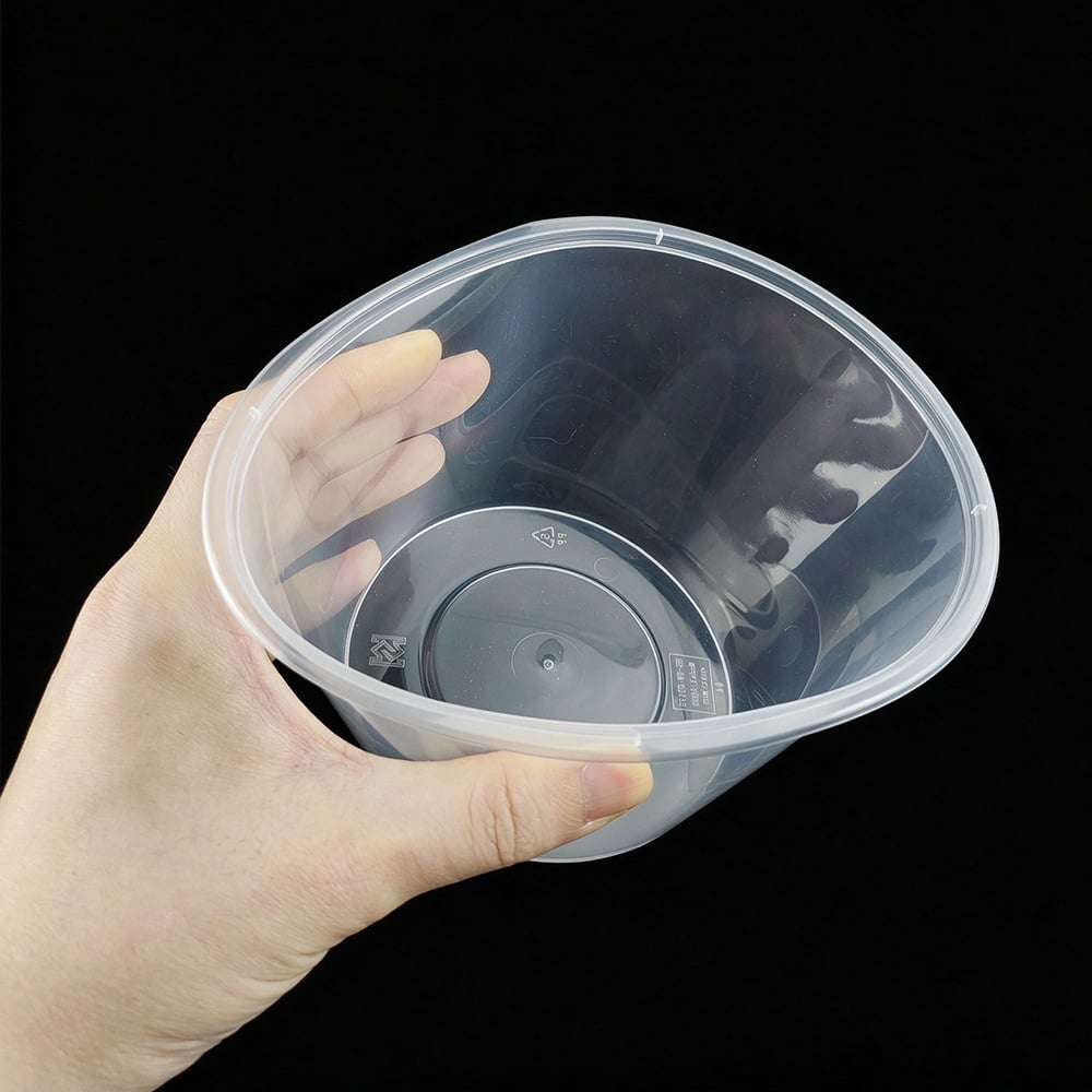 Hand holding an empty clear round PP food container