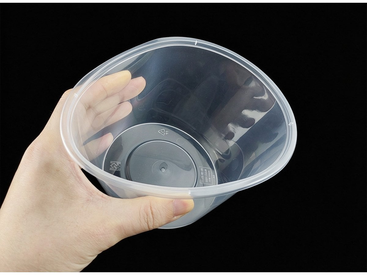 Hand holding a clear round container, interior and base view