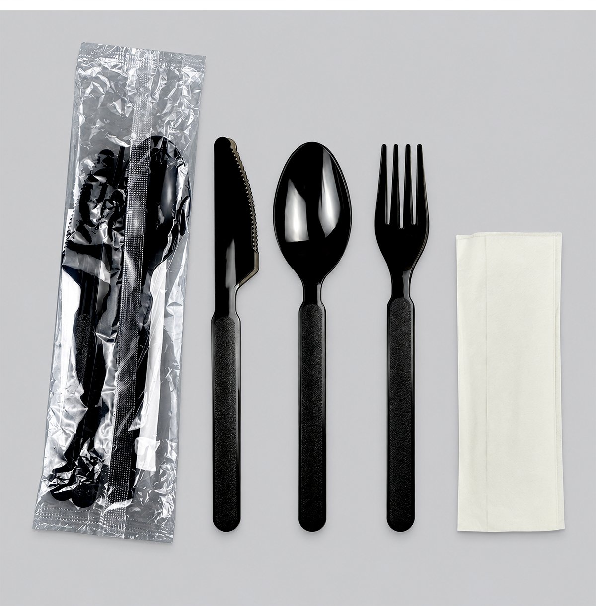 Black knife, spoon, fork and napkin beside wrapped kit